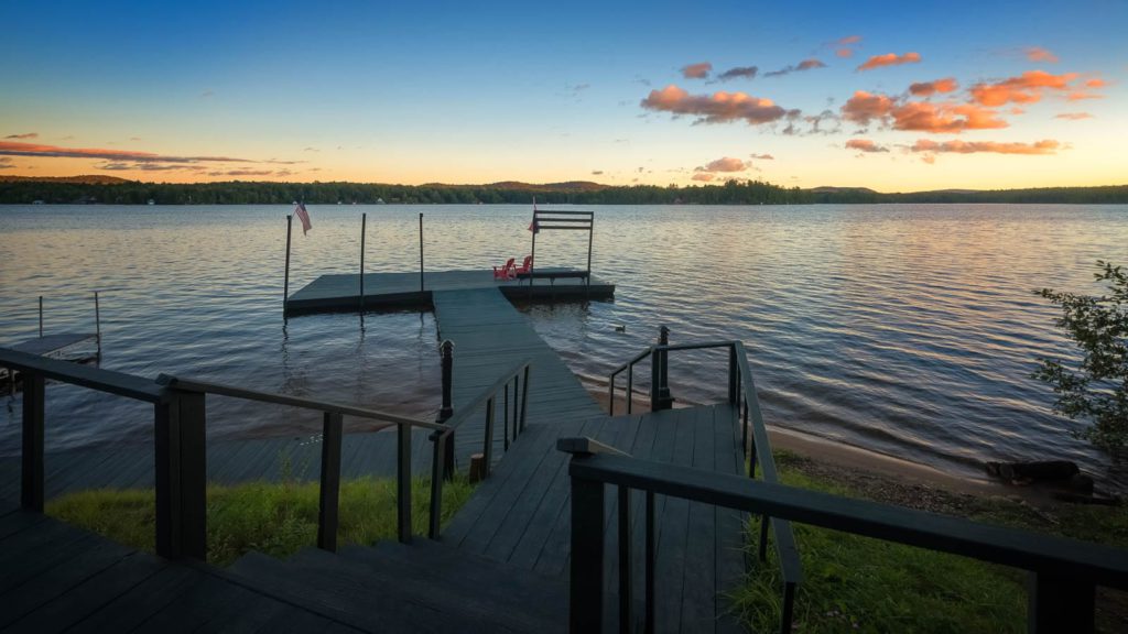 A dock leading to a lake at sunset.