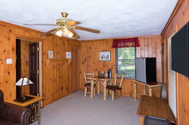 A living room with wood paneling and a ceiling fan.