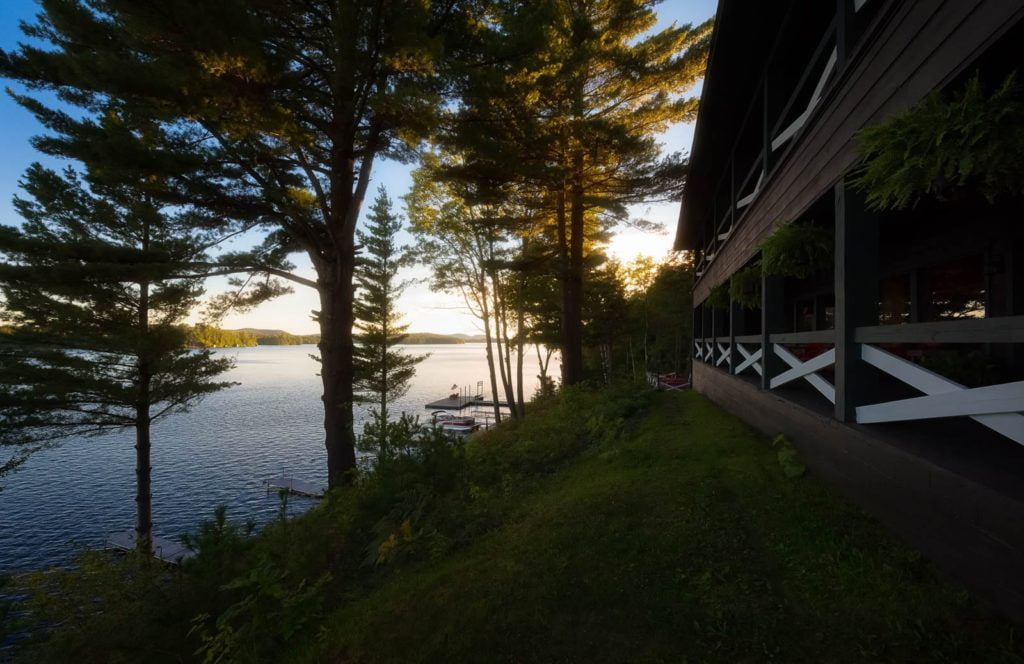 A house overlooking a lake with trees in the background.