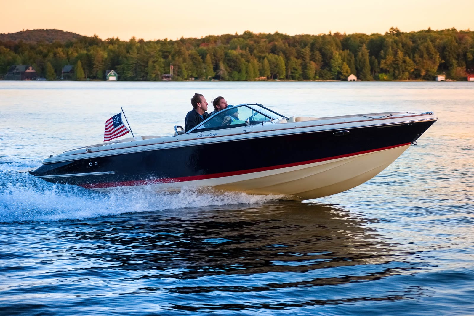 Two people are driving a speed boat on the water.