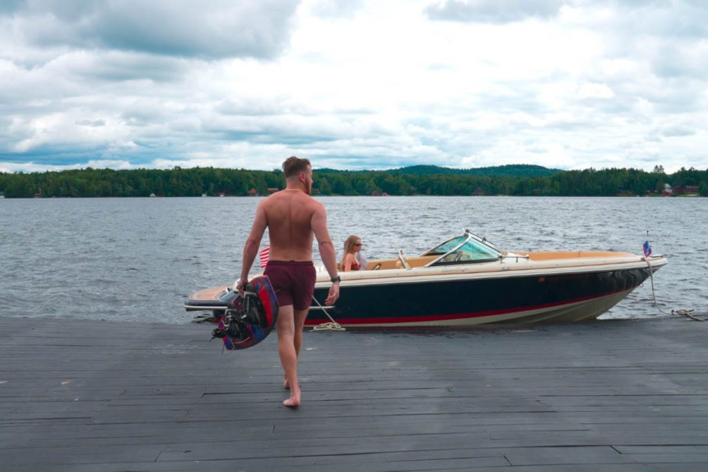 A man is walking to a dock with a boat in the background.