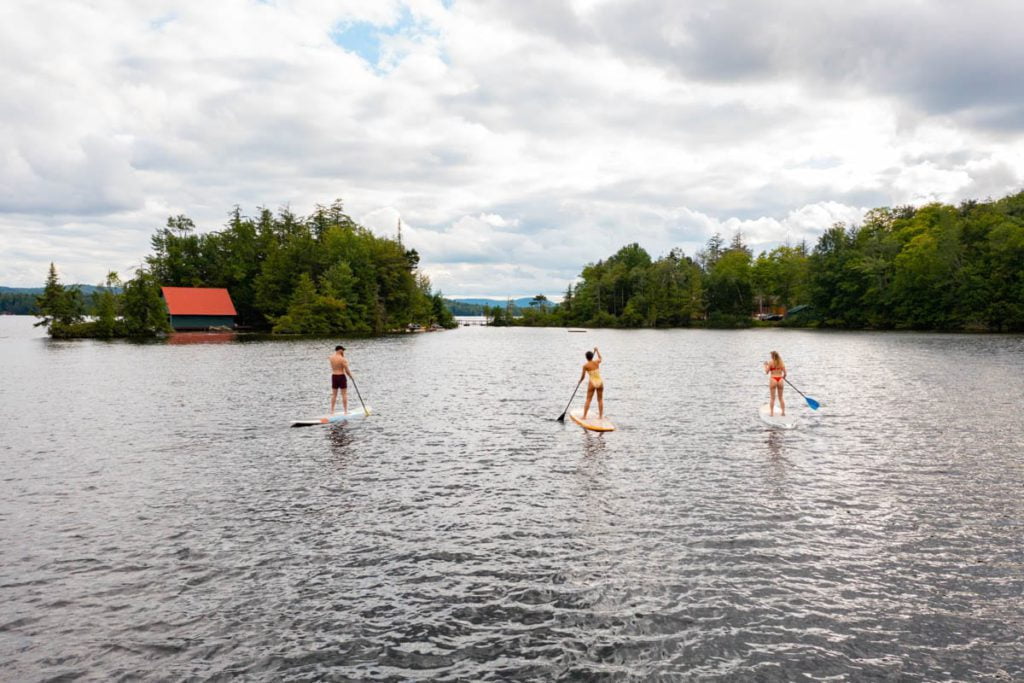 Three people stand up paddle boarding on a lake.