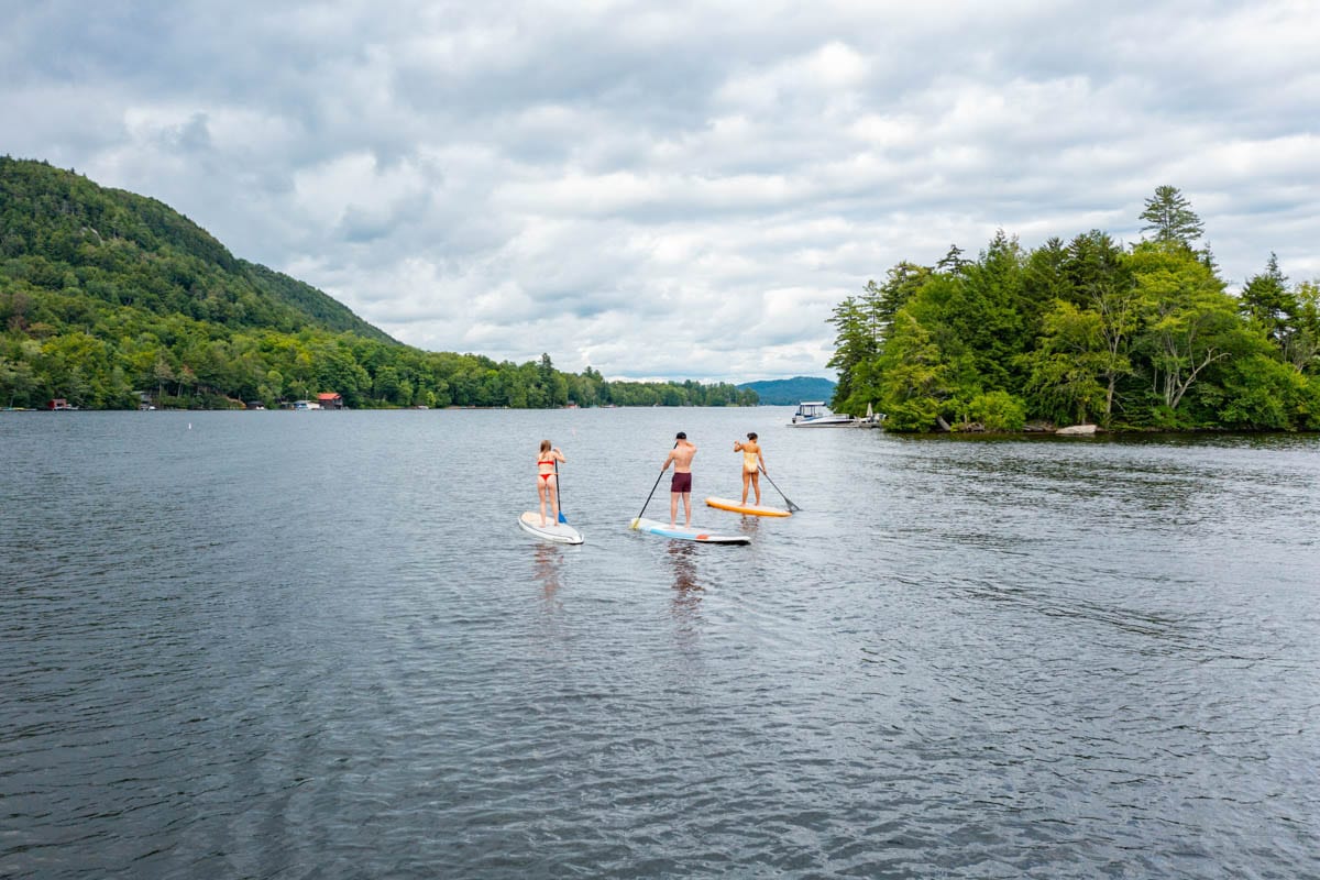 Three people stand up paddle boarding on a lake.