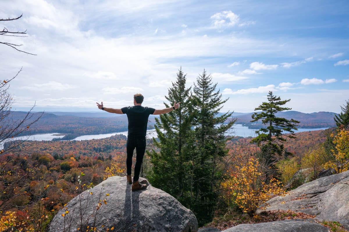 A man standing on top of a mountain with his arms outstretched.