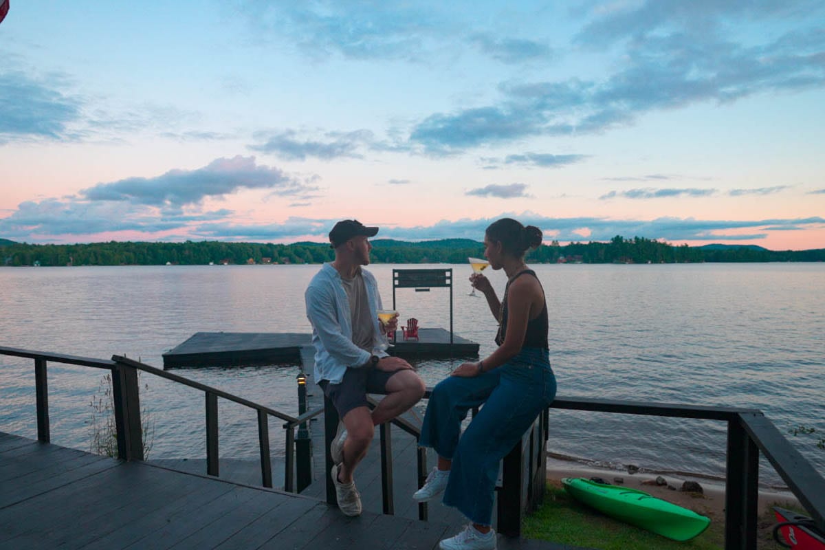 Two people sitting on a dock overlooking a lake.