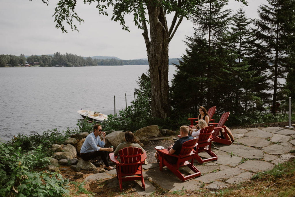 A group of people sitting around a fire pit near a lake.