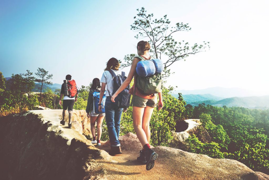 A group of people hiking with backpacks on a cliff.