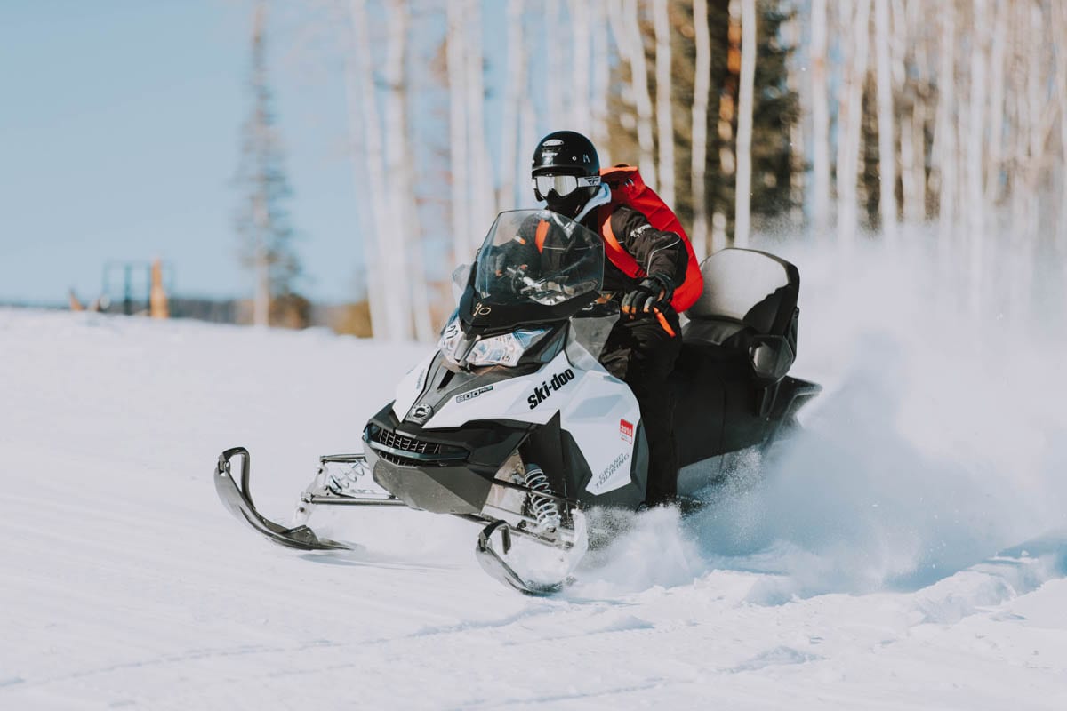 A person riding a snowmobile on a snowy trail.